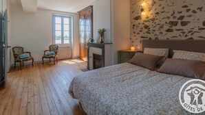 Een slaapkamer met een bed, een openhaard en een stenen muur.