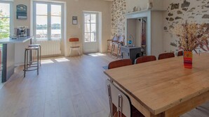 Een ruime keuken met een grote houten tafel, een stenen muur en uitzicht op de omgeving.