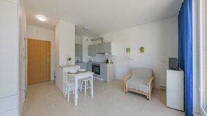 A compact living space with a kitchenette, a dining area, a seating area, and a television. - Apartamenty Sun & Snow Nowe Hallerowo (Wladyslawowo)