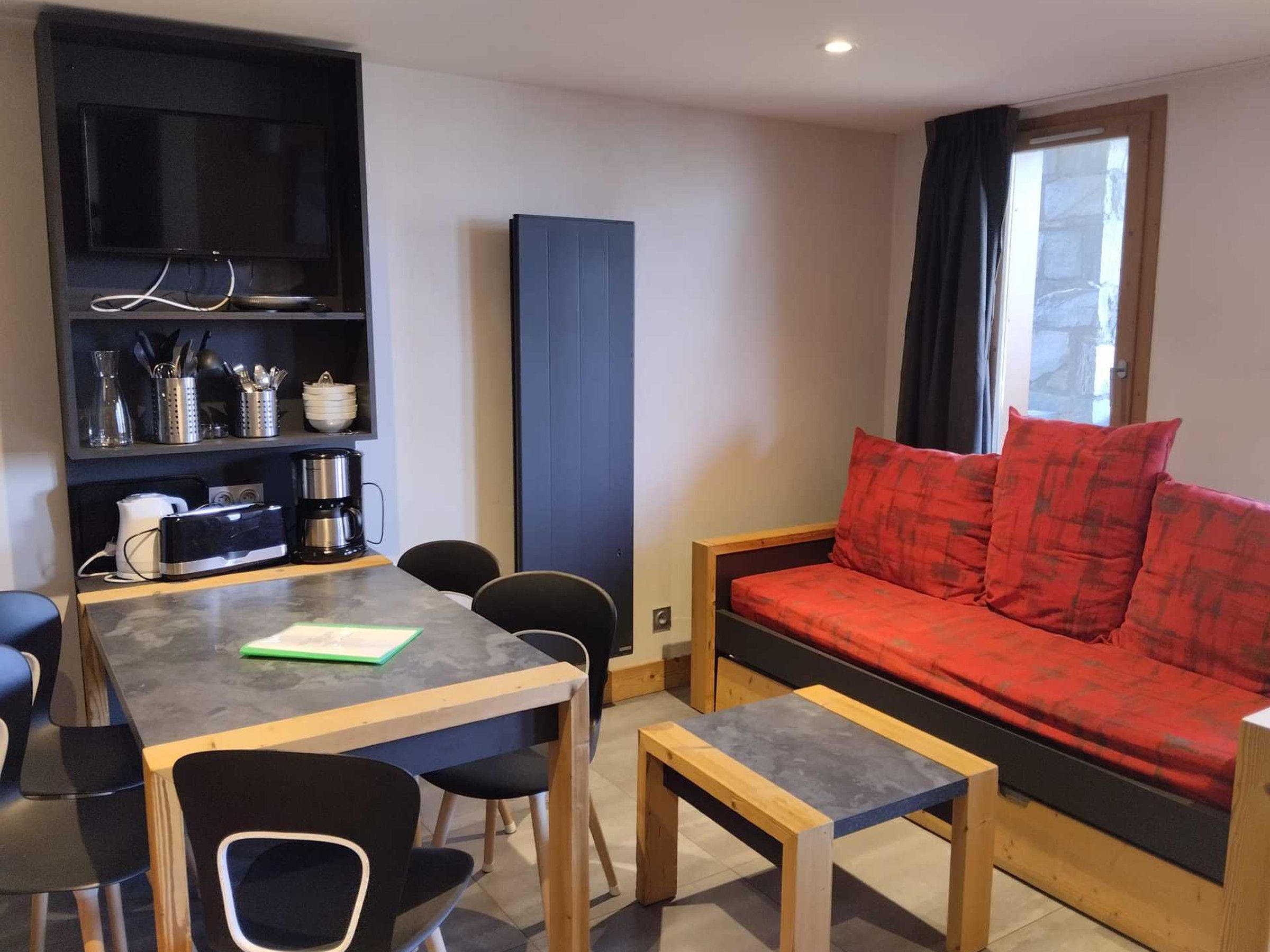 A compact living space with a dining table, chairs, a sofa, and a built-in bookshelf.