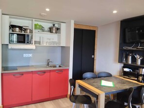 A compact kitchen with a microwave, stove, and shelves above the sink. - Cozy apartment in La Plagne, slopes access, pets allowed (La Plagne Montchavin Les Coches)