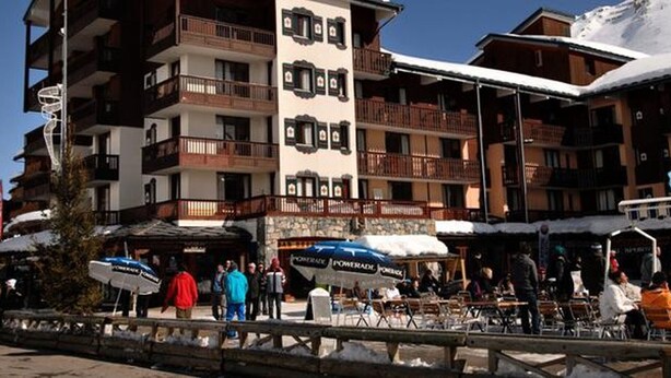 Un hotel de varios pisos con balcones, una torre central y zonas de estar al aire libre.