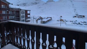 Paisaje montañoso nevado con un complejo de esquí, que incluye un edificio con balcón y una cerca de madera.