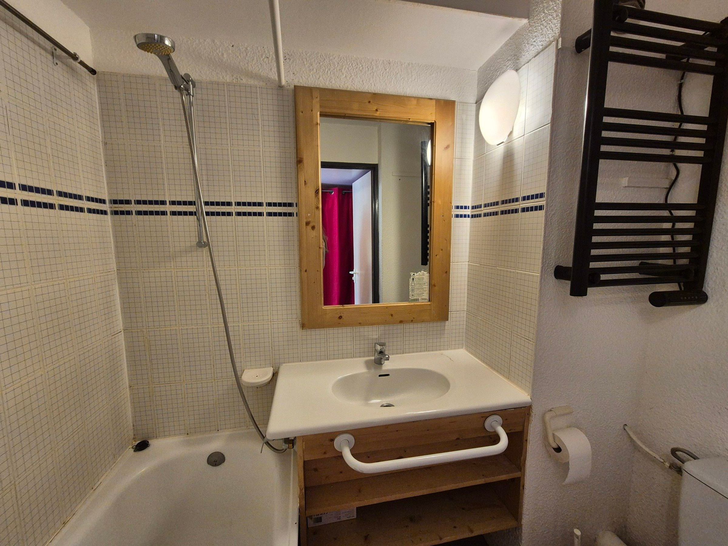 A bathroom with a bathtub, a sink, a mirror, and a towel rack.
