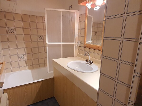 A bathroom with a bathtub, a sink, and a mirror.