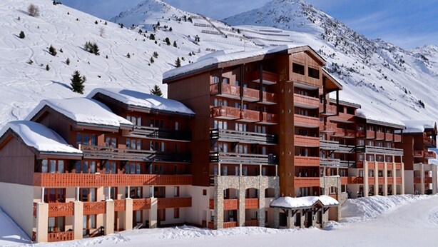 A multi-story hotel with balconies, set against a snowy mountain backdrop. - Ski-in apartment, 5 pers, pets allowed (Belle Plagne)