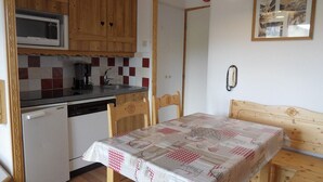 A compact kitchen with wooden cabinets, a microwave, a sink, and a table with a checkered tablecloth. - Ski-in apartment, 5 pers, pets allowed (Belle Plagne)