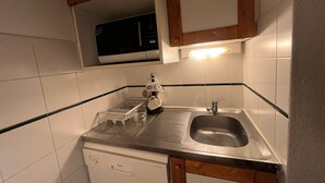 A compact kitchen with a dishwasher, a sink, and a microwave.