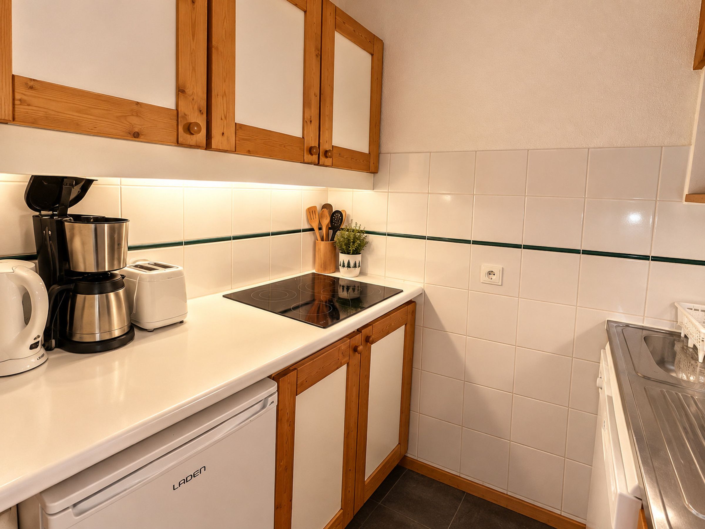 A compact kitchen with a coffee maker, toaster, and a small induction cooktop.