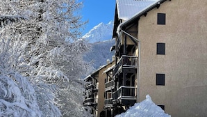 Un bâtiment enneigé, doté de balcons, avec une montagne en arrière-plan.