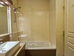 Bathroom features a bathtub, glass-enclosed shower, and a sink with mirror.