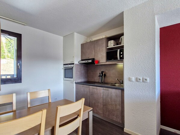 Compact kitchenette with microwave, oven, and sink, perfect for preparing meals.