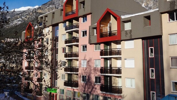Un hotel a più piani con balconi e montagne sullo sfondo.