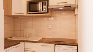 Una cucina compatta con forno a microonde, lavello e lavastoviglie.