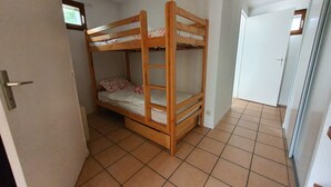 A small, narrow room with a bunk bed and a door leading to another room. - Apartment near lifts, free wifi, pets allowed (Briançon)