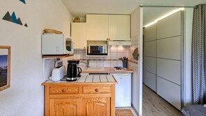 A compact kitchen with white cabinets, a microwave, a stove, and a coffee maker. - Renovated studio in Flaine center with balcony for 5 people (Flaine)