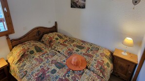 Un lit simple avec une couvre-lit à motifs, une petite table de chevet avec une lampe et un tableau accroché au mur.