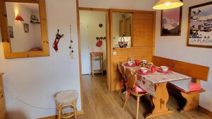 Un coin repas avec une table en bois dressée pour quatre personnes, un miroir au mur et un objet décoratif suspendu.