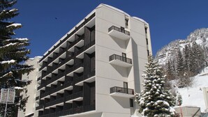 A multi-story building with a modern architectural design, featuring a series of balconies and a stone facade. - Comfortable studio in Flaine, balcony, near slopes (Flaine)