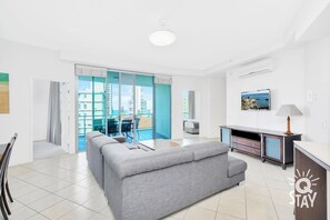 Relax in this stylish living area with a sofa, flat-screen TV, and sliding glass door leading to a balcony with city views.