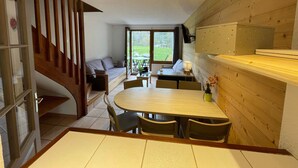 Un intérieur chaleureux avec un coin repas, un canapé et un escalier.