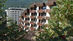 Un hôtel à plusieurs étages, doté de balcons, situé dans un cadre montagneux.