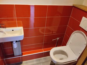 A bathroom with a white sink, a toilet, and red tiled walls. - Comfortable apartment with free parking in La Plagne (La Plagne Montchavin Les Coches)