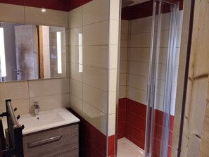 Casa de banho com lavatório branco, espelho e cabine de duche.