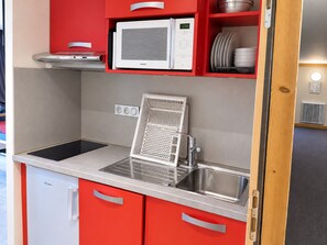 A compact kitchen with a microwave, sink, and a built-in grill. - Comfortable apartment, near slopes, terrace, pets allowed (La Plagne Montchavin Les Coches)