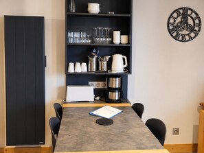 A modern kitchen with a built-in oven, a coffee maker, and a clock on the wall. - Comfortable apartment, near slopes, terrace, pets allowed (La Plagne Montchavin Les Coches)