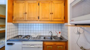 A compact kitchen with wooden cabinets, a gas stove, a dishwasher, and a built-in microwave. - Renovated studio 4 people, near slopes, balcony, ski locker (Flaine)