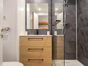 Bathroom features a vanity with drawers, mirror, and glass shower enclosure.