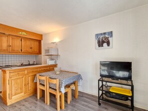 Enjoy meals at the small dining table for two, with a flat-screen TV and bear-themed artwork nearby.
