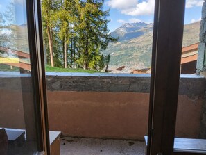 A room with a view of mountains and trees through a window. - Bright Apartment 5p · Wellness Area · Pets Allowed (La Plagne Montchavin Les Coches)
