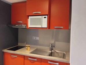 A compact kitchen with a microwave, sink, and orange cabinets. - Bright Apartment 5p · Wellness Area · Pets Allowed (La Plagne Montchavin Les Coches)
