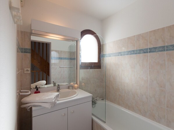 A bathroom with a sink, mirror, and shower.