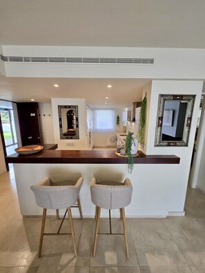 A modern kitchen with a central island, two bar stools, and a large mirror. - 28 - Piso en Alanda los Flamingos, Benahavis (Benahavís)