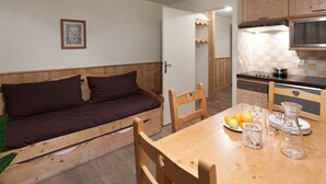 A compact living space with a sofa, dining table, chairs, and a kitchenette.