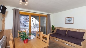 A cozy room with a wooden table, a sofa, and a window with curtains.