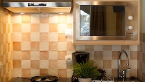 A kitchen with a microwave, stove, sink, and a potted plant.