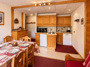 A compact kitchen with wooden cabinets, a microwave, a coffee maker, and a dishwasher.