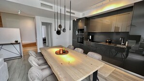 Et moderne køkken med et træspisebord, grå polstrede stole og stålemmer.