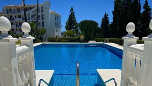 A swimming pool with clear blue water, surrounded by white balustrades and decorative spheres. - 53 - Apartment in Riviera with pool and sea view (Mijas Costa)