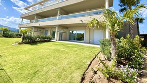 A modern multi-story building with balconies, large windows, and a well-maintained lawn. - 54 - Apartment on the cala golf course (La Cala de Mijas)