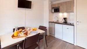 Une cuisine moderne avec un coin repas, équipée d’un four à micro-ondes, d’un évier et d’un téléviseur à écran plat.
