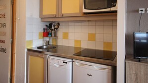 Cozinha compacta com máquina de lavar louça, micro-ondas e um pequeno armário com utensílios de cozinha.