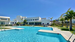 A swimming pool with clear blue water, surrounded by modern buildings and palm trees. - 55 - Apartment in La Cala de Mijas (La Cala de Mijas)