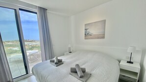 A modern hotel room with a large bed, a view of the city through the balcony, and a painting on the wall. - 55 - Apartment in La Cala de Mijas (La Cala de Mijas)