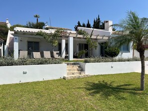 Ein modernes Haus mit weißer Fassade, einer Steintreppe zum Eingang und einem gepflegten Rasen.