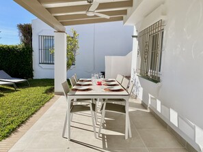Eine Terrasse mit Esstisch, umgeben von weißen Wänden und einem gefliesten Boden.